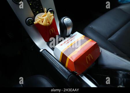 Ein McDonald's-Menü im Auto. Hier pommes frites und ein Hamburger mit einem Viertel Pounder am Schalthebel. Stockfoto