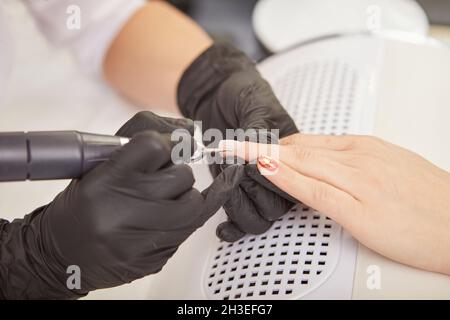 Manikurist mit Nagelhautentferner während der Maniküre für den Kunden Stockfoto