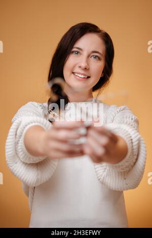 Frau in weißem Pullover hält Metall Ausstechform auf gelbem Hintergrund. Stockfoto