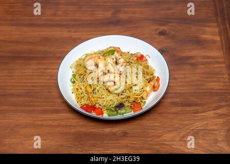 Chinesische Reisnudeln mit Garnelen und Gemüse im Wok und mit Sojasauce anbraten Stockfoto