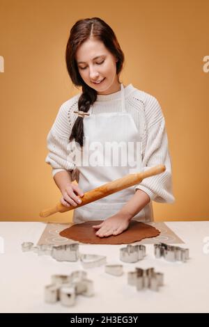 Die junge Bäckerin knetet Lebkuchenteig für würzige Kekse. Stockfoto