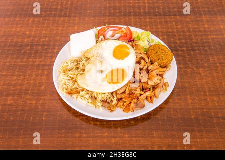 Combo-Menü Kebab-Gericht mit Huhn und Lamm, Falafel, Spiegeleier, Basmati-Reis, Ziegenkäse, Tomatensalat mit roter Zwiebel und Salat Stockfoto