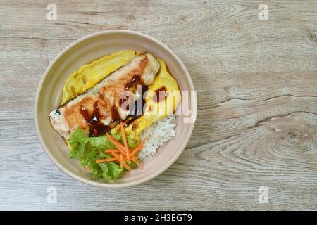 Gegrillter Lachs mit Eiersoße Teriyaki, die auf japanischen Reis in einer Schüssel übergeht Stockfoto