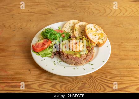 Rote Thunfisch-Tartare mit Guacamole, Garnelen, Wakame-Algen und Salat mit Salat und Tomaten Stockfoto