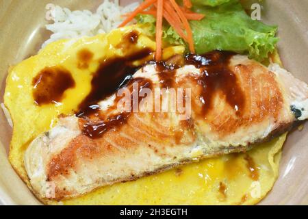 Gegrillter Lachs mit Eiersoße Teriyaki, die auf japanischen Reis in einer Schüssel übergeht Stockfoto