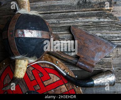 Kampf Axt gehörnten Helm Signalhorn und Schild mit viking Runen auf rauen Holztisch Draufsicht bedeckt Stockfoto