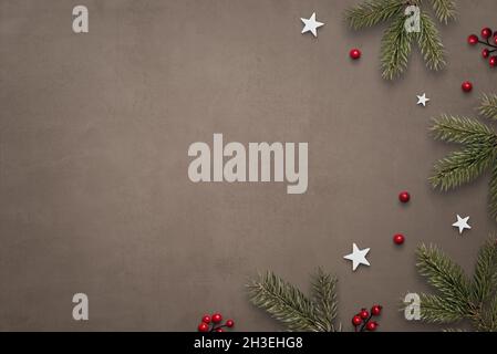 Rustikaler, Vintage-Weihnachtshintergrund mit Christbaumzweigen, Sternen und roten Beeren. Platz daneben kopieren. Draufsicht, flache Lay-Komposition Stockfoto