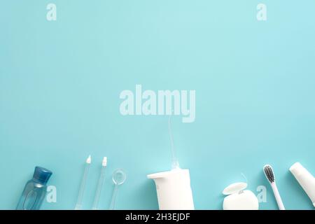 Elektrischer Oral Irrigator, Zahnbürste, Flosser, Flüssigkeit auf blauem Hintergrund. Zahnpflegekonzept. Stockfoto