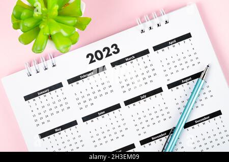 12 Monate Tischkalender 2023 mit Stift auf rosa Hintergrund. Stockfoto