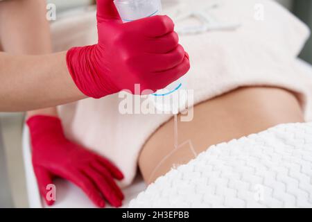 Junge Frau bekommt fettreduktive Haut Lifting Körperbehandlung durch einen Kosmetologen. Attraktive weibliche Patientin, die sich gerne an schlankeren Körperkonturierung erfreut Stockfoto