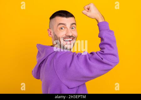 Foto Porträt junger Mann trägt lila Kapuzen zeigt starke Bizeps isoliert lebendige gelbe Farbe Hintergrund Stockfoto