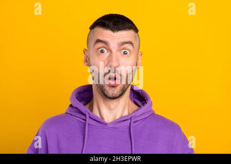 Foto von beeindruckt jungen Brunet Kerl tragen violette Hoodie isoliert auf gelbem Hintergrund Stockfoto