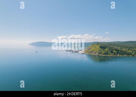 Der Baikalsee ist ein wunderschönes blaues Juwel, eingerahmt von malerischen Bergen und Wäldern. Epische filmische Luftaufnahme des Baikalsees. Luftaufnahme des blauen Sees und Stockfoto