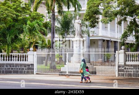 Indische Frau und kleines Mädchen, die an der Statue der Königin Victoria vor dem Regierungsgebäude, Port Louis, Mauritius, den Mascarene-Inseln vorbeigehen. Stockfoto