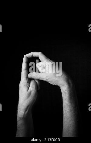 Dramatisches Schwarzweiß-Bild der männlichen Hand Fingerbuchstabierung BSL britische Gebärdensprache Buchstabe D isoliert vor dunklem Hintergrund Stockfoto