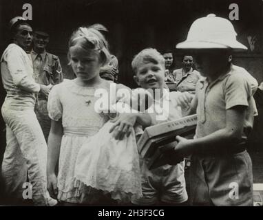 Ein Vintage-Foto um den Februar 1942, das britische Kinder zeigt, die vor der japanischen Invasion von Malaya und dem Fall von Singapur per Schiff aus Singapur evakuiert wurden. Britische Matrosen und Soldaten erscheinen im Hintergrund. Stockfoto