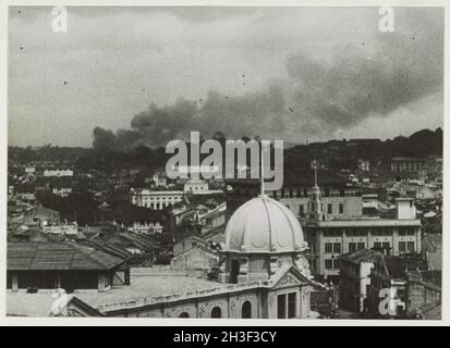 Ein Vintage-Foto um den Februar 1942, das den Rauch zeigt, der während eines Luftangriffs der japanischen Luftwaffe während der Invasion von Malaya und des Sturzes von Singapur über die Stadt Singapur aufsteigt. Stockfoto