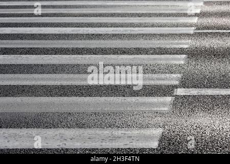 Weiße Streifen auf schwarzem Asphalt ist eine Fußgängerüberfahrt. Stockfoto