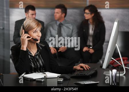 Angestellte an der Rezeption am Telefon sprechen Stockfoto
