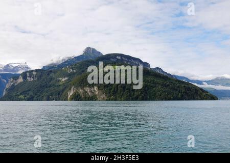 Die Gipfel der Hochalpen sind etwas schneebedeckt. Die Hügel sind bewaldet, wie man sie von Brunnen im Kanton Schwyz in der Schweiz aus gesehen hat. Stockfoto