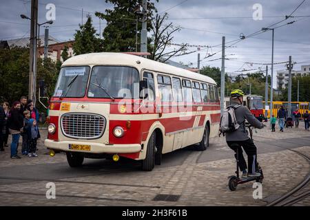 Breslau, Polen - 19. September 2021: Eine Schlange von Passagieren, die am Busbahnhof in den alten roten und cremefarbenen Skoda-Bus steigen. Mann auf dem Roller im Vordergrund. Stockfoto