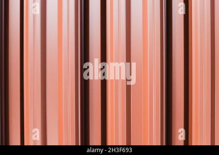 Glänzender Zaun aus roten Metallplanken, abstrakter Hintergrund-Fototextur Stockfoto