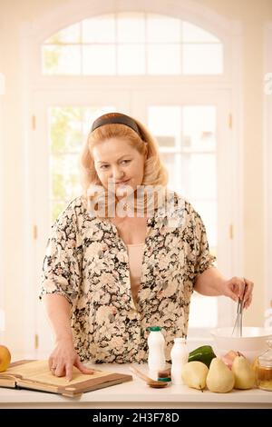 Frau überprüft Rezept in der Küche Stockfoto