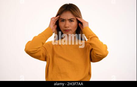 Junge attraktive asiatische Frau mit Kopfschmerzen im Studio Stockfoto