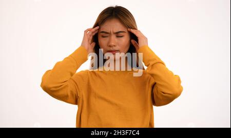 Junge attraktive asiatische Frau mit Kopfschmerzen im Studio Stockfoto