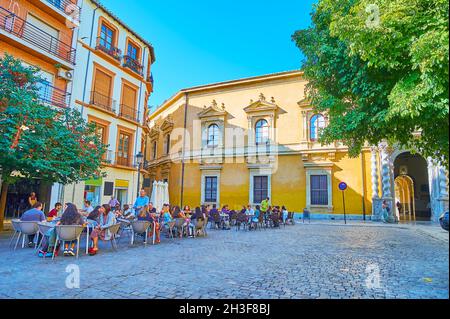 GRANADA, SPANIEN - 27. SEPTEMBER 2019: Universitätsplatz mit Cafés im Freien und historischem Gebäude der Juristischen Fakultät der Universität Granada, dekoriert mit Sol Stockfoto