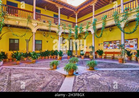 GRANADA, SPANIEN - 27. SEPTEMBER 2019: Der malerische Innenhof des Königlichen Musikkonservatoriums Victoria Eugenia, verziert mit Mosaiken auf dem Boden, Steinsäule Stockfoto