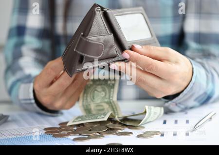 Frau goss Dollarscheine und Münzen aus der Ledertasche auf den Tisch mit Dokumenten aus der Nähe Stockfoto