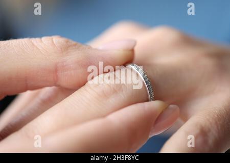 Frau Hand legte silbernen Ring auf ihren Finger Nahaufnahme Stockfoto