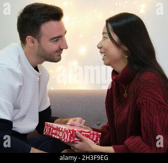 Junge, multirassische, glückliche Paare tauschen Weihnachtsgeschenke aus. Stockfoto