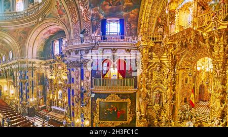 GRANADA, SPANIEN - 27. SEPTEMBER 2019: Panorama-Innenraum der spektakulären historischen Basilika San Juan de Dios mit reich verzierten goldenen Altaraufsatz und Fresken Stockfoto