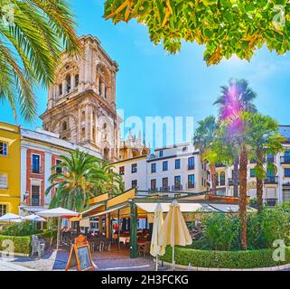 Der belebte Plaza de la Romanilla mit Blick auf den Glockenturm der Kathedrale, historische Gebäude und Restaurant im Garten, Granada, Spanien Stockfoto