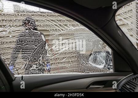 Winchester, Hampshire, Großbritannien. 2021. Autofahrer sehen während einer Autowäsche Arbeiter, Seifenlauge und Wasser aus der Sicht Stockfoto