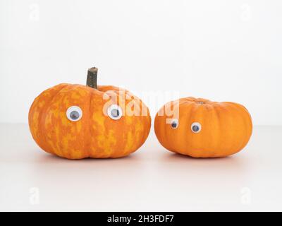 Zwei kleine Kürbisse, Squashes mit aufgeklebten Augen. Halloween vielleicht. Stockfoto