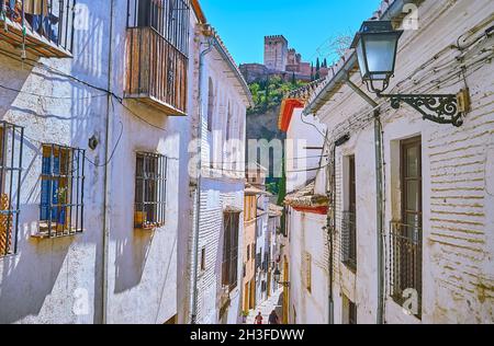 Der Blick auf den Sabika-Hügel und die mittelalterlichen Türme der Alhambra durch die weiß getünchten Mauern der alten Häuser von Albaicin, Granada, Spanien Stockfoto