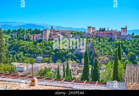 Der prächtige mittelalterliche Alhambra-Komplex ist von üppigem Grün und Silhouetten der Sierra Nevada Berge umgeben, im Hintergrund gesehen, Granada, Sp Stockfoto