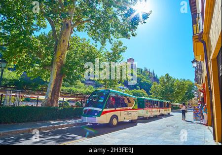 GRANADA, SPANIEN - 27. SEPTEMBER 2019: Der moderne Touristenzug auf der Stadtrundfahrt, auf der Straße Paseo de los Tristes von Albaicin, am 27. September in Granada Stockfoto