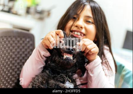 Liebenswert lächelnd kleines Mädchen Kind schulmädchen hält und spielt mit Haustier Hund. Beste Freunde. Stockfoto