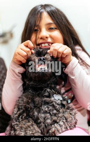 Liebenswert lächelnd kleines Mädchen Kind schulmädchen hält und spielt mit Haustier Hund. Beste Freunde. Stockfoto