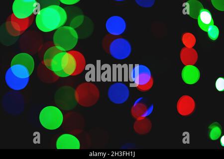 Grün-blaue und rote Bokeh Kreise auf schwarzem Hintergrund. Dekorativer Hintergrund Stockfoto