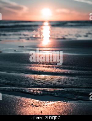 Herrlicher Sonnenuntergang in Italien, Bibione, am Meer mit herrlichem Licht und Wellen vorne, die sich in eine wunderschöne romantische Landschaft vermischen. Stockfoto