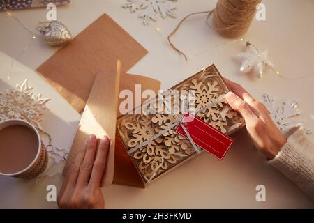 Weibliche Hände wickeln Weihnachtsgeschenke zu Hause. Gemütliches Zuhause. Handgemachte Geschenke. Weihnachtsvorbereitungen. Hochwertige Fotos Stockfoto