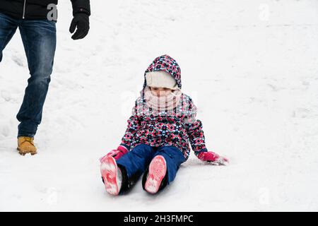 Überraschendes Rutschen und Fallen im Schnee beim Wandern an einem Wintertag Stockfoto