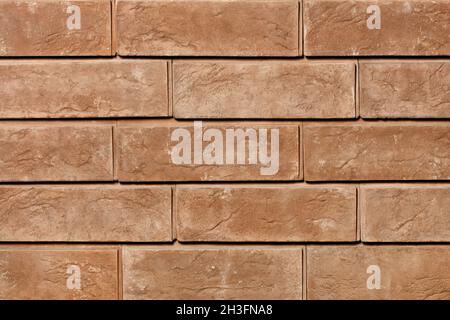 Braune Ziegelwand mit rauer Oberfläche und ausdrucksstarken Schatten. Nahaufnahme. Stockfoto