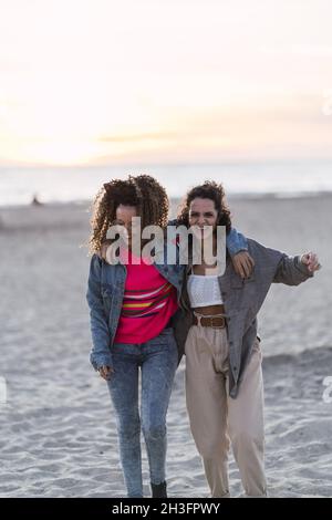Vertikale Aufnahme von zwei spanischen kaukasischen Weibchen, die auf dem Sand posieren Stockfoto