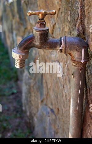 Nahaufnahme Profil eines geschlossenen Bronze Wasserhahn an einer Wand im Freien. Selektiver Fokus. Vertikal. Wasser sparen Stockfoto